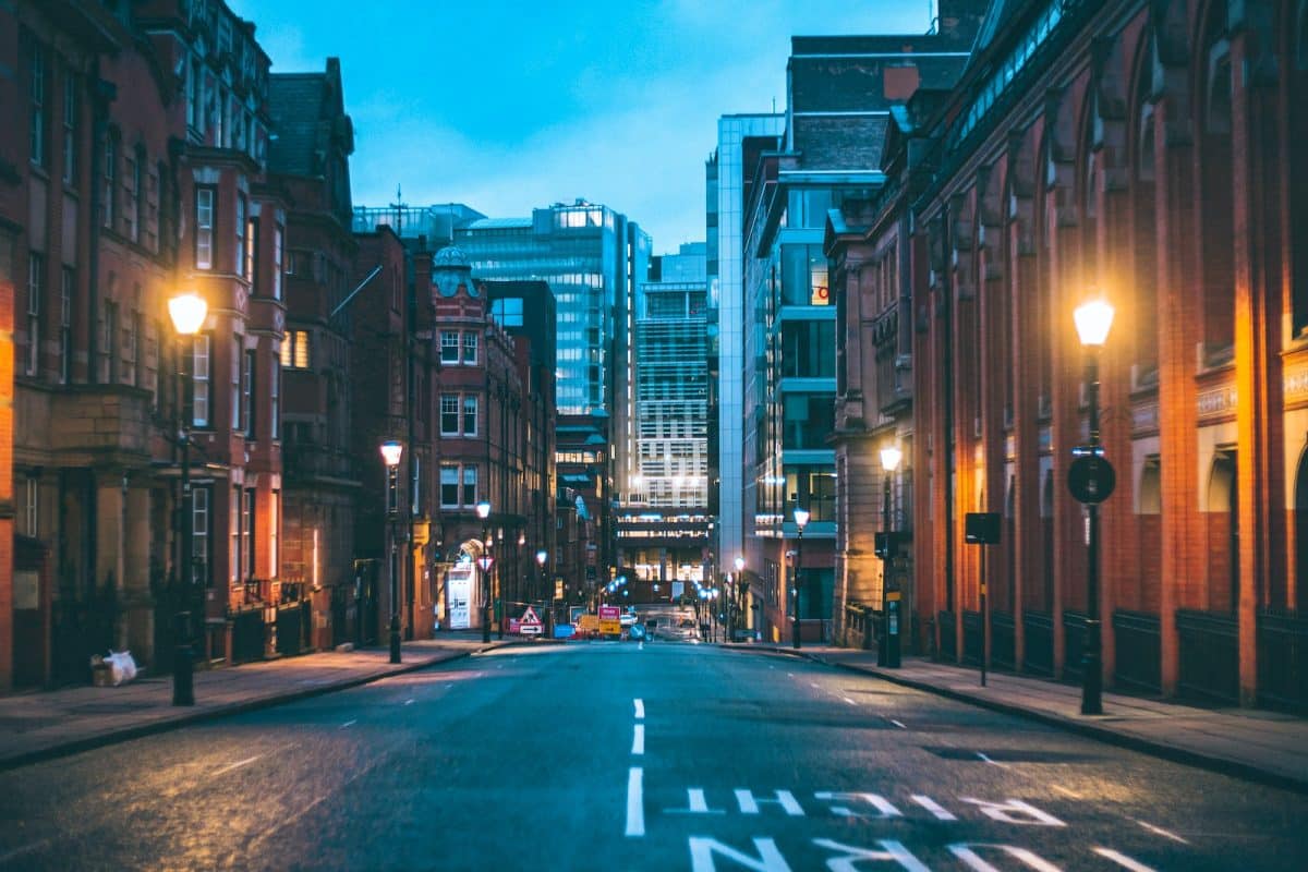 cars on road between high rise buildings during night time